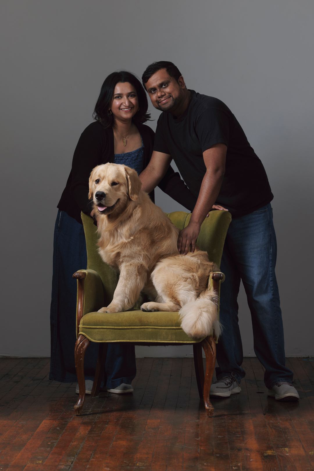 Bijili on a green velvet chair with both of his humans behind him