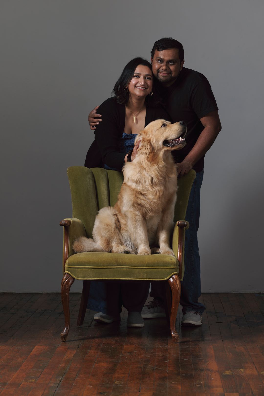Bijili sitting on a green velvet chair with his family